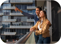 Smiling couple standing on balcony of modern apartment"