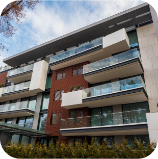 Multi-story modern apartment building with glass balconies.