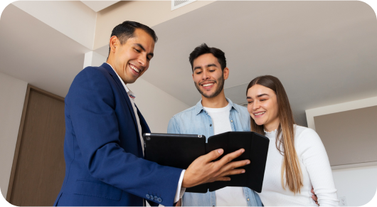 Three professionals smiling and looking at a laptop in a modern office